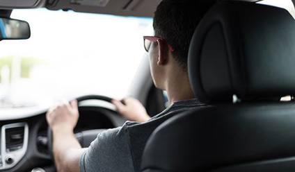 A young man behind the wheel of a car.