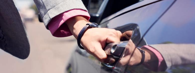 A person with their hand on a car door handle