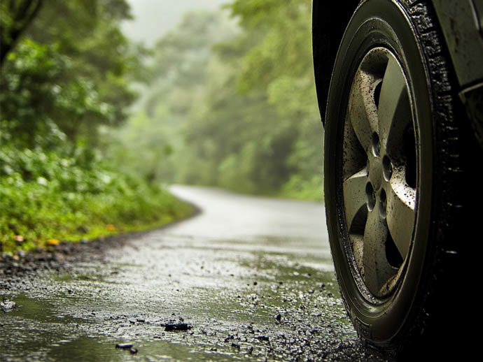 Car tyre on a muddy road with trees in the background