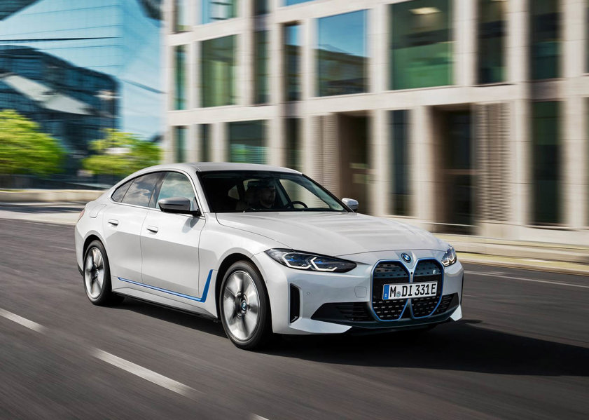 White BMW i4 driving on the road with buildings in background