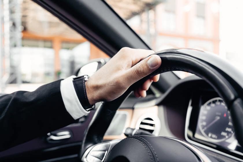 Person dressed smart holding steering wheel