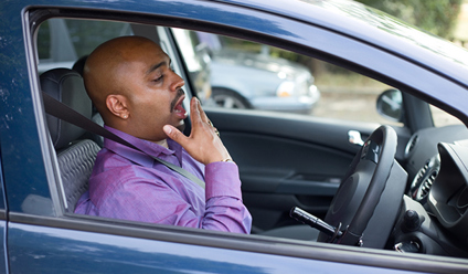 man sat in blue car yawning