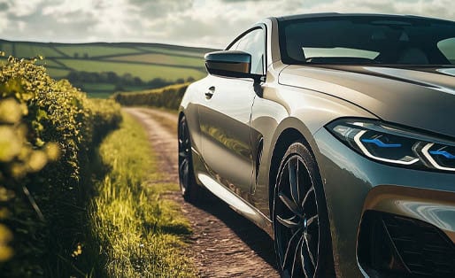 BMW coupe parked on a country lane with rolling hills in the background