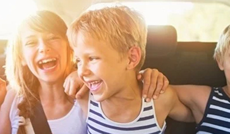 Three laughing children sat in the back of the car.