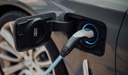 A close up of an electric car with its charging cable attached.