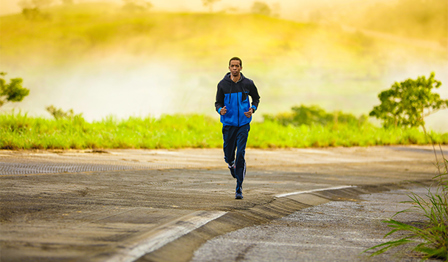 A photo of a person running on a street with a car passing by for an article on staying safe while running on the road.