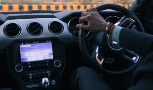 Person in a suit driving a nice car