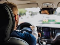 Man driving a car with two hands on the steering wheel
