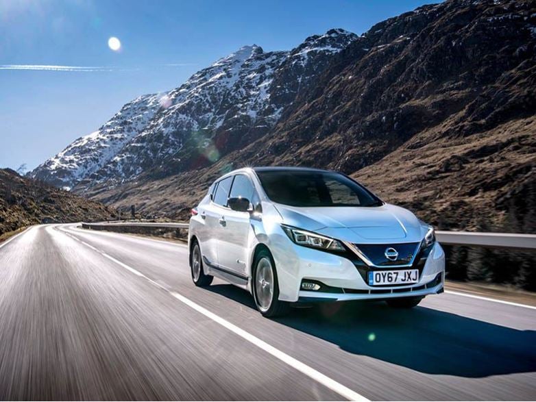 white nissan leaf driving on road