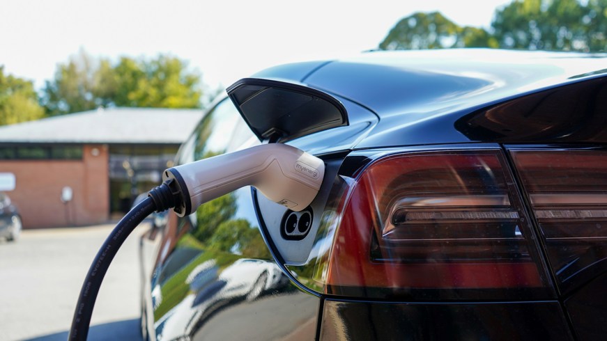 Black electric car charging in a car park