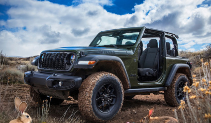 Green Jeep Wrangler with doors off parked on a muddy trail, surrounded by Easter eggs and rabbits