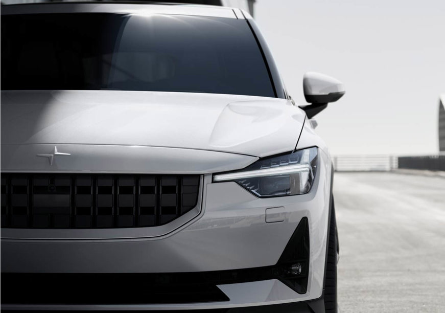 Polestar 2 lease car in white with headlights on