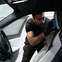 a man cleans seat inside car