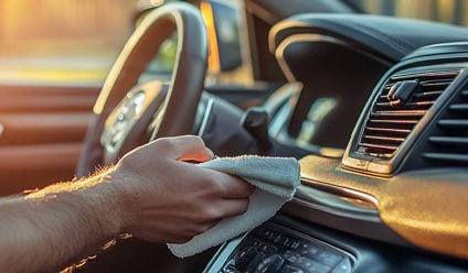 Person cleaning dashboard of a car with a cloth