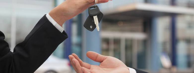 One hand dropping car keys into another at a car dealership