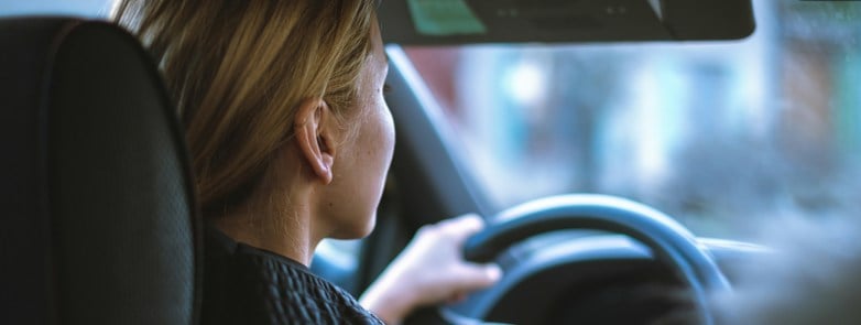 a woman sitting in a car with a steering wheel