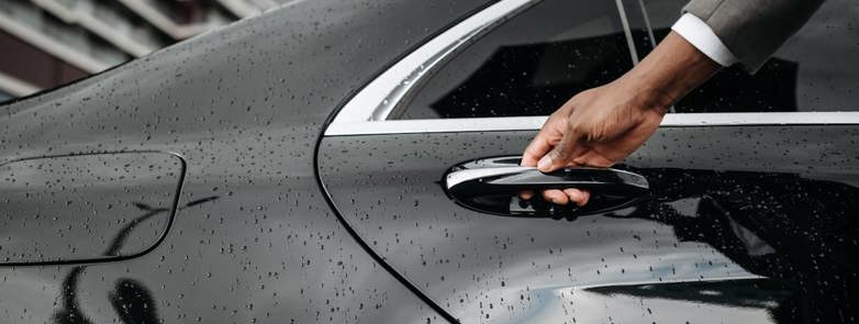 Person in suit opening the rear door of a stylish saloon car