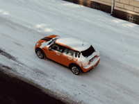 Aerial view of an orange car driving on a snowy street in Jönköping, Sweden.