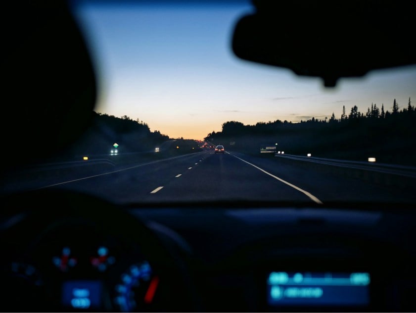 car dashboard with road in the background as the sun sets