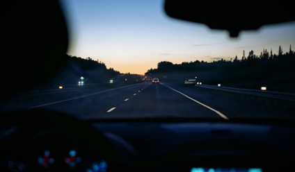 car dashboard with road in the background as the sun sets