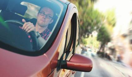 A close up of a young man driving a car.