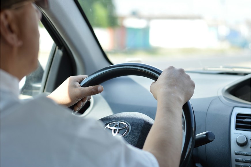 Man driving car with two hands on the steering wheel