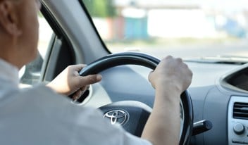 Man driving car with two hands on the steering wheel