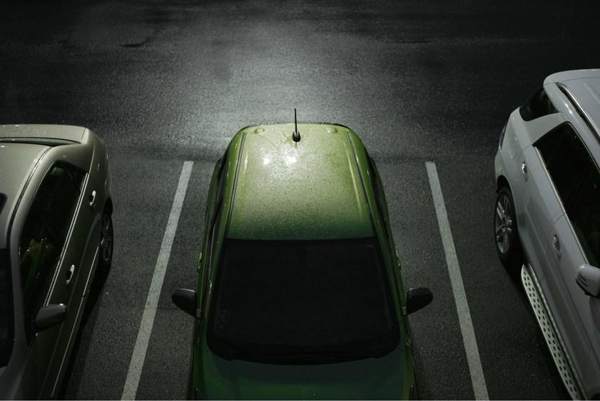 Dark car park with a green car parked in a parking space