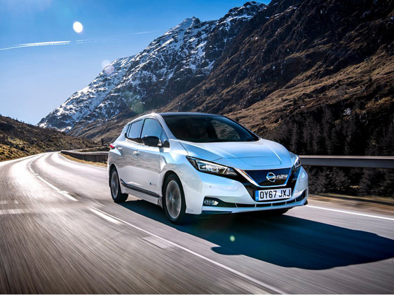 silver nissan leaf driving through a mountain range