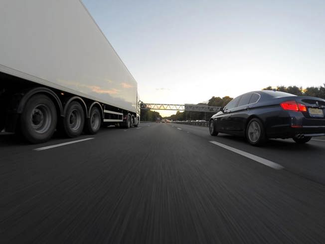 Navy saloon car overtaking a white lorry on a motorway in the UK