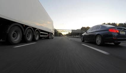 Navy saloon car overtaking a white lorry on a motorway in the UK