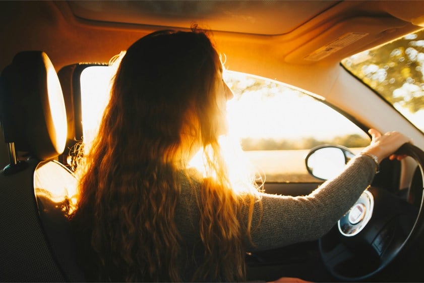 woman driving car with sun coming through window