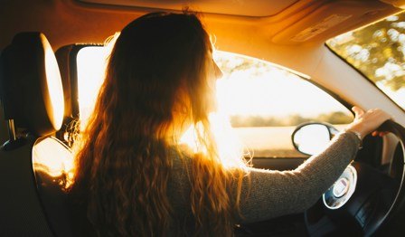 woman driving car with sun coming through window
