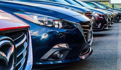 A row of cars, parked in a dealership forecourt.