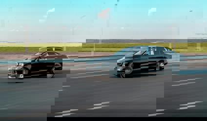 Black saloon car driving on a modern road