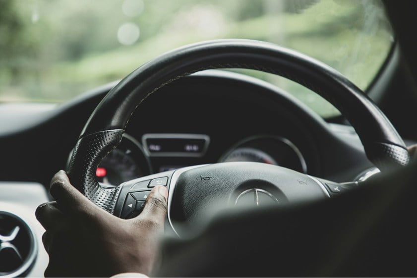 Person driving car with hands on the steering wheel