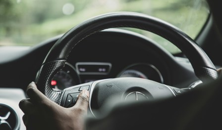 Person driving car with hands on the steering wheel