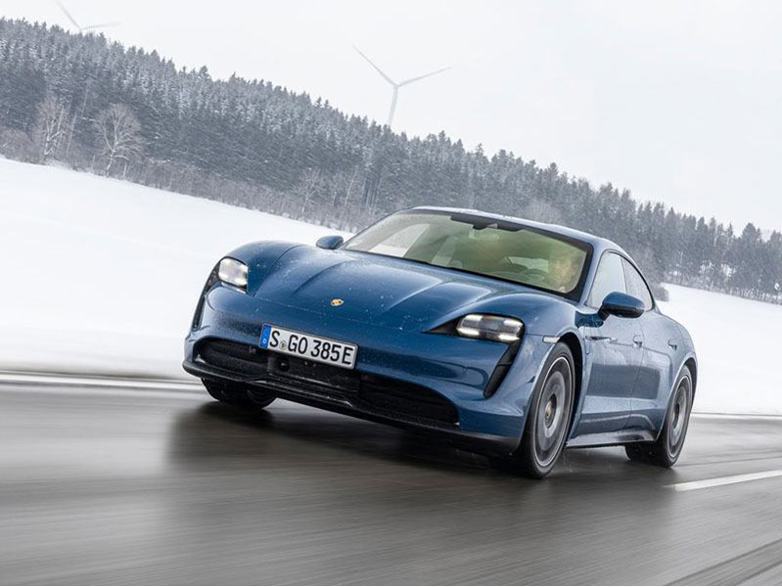 dark blue porsche taycan driving in snowy conditions