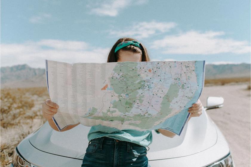 woman on a car reading atlas