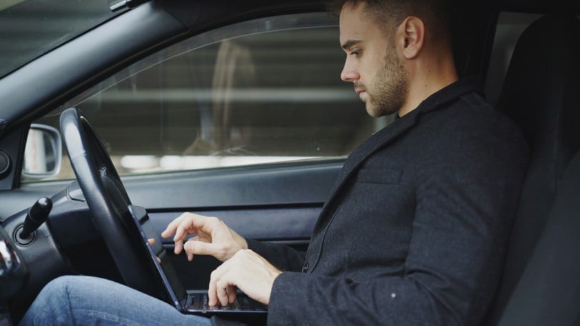 man working on laptop inside a car