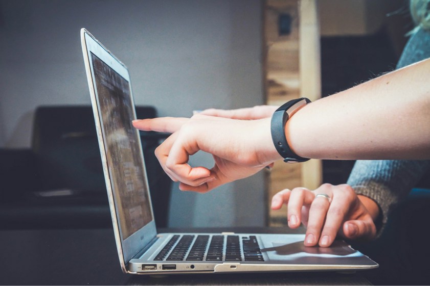 two people pointing at laptop screen