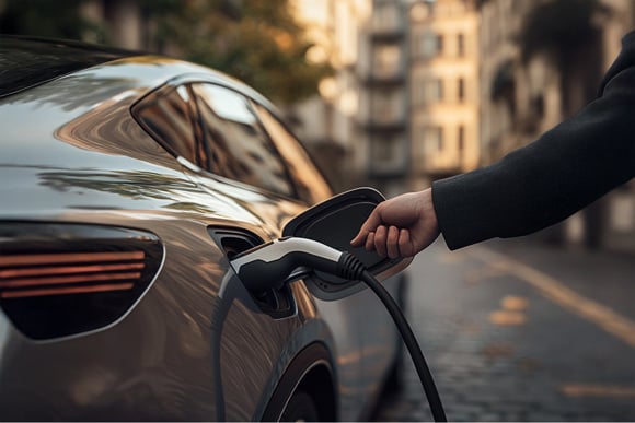 Person Plugging in an Electric Car on a Cobblestone Street